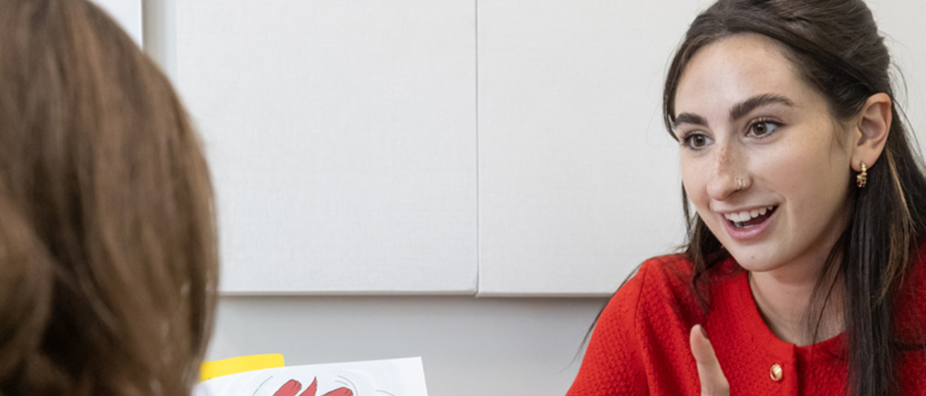 Speech-language pathologist works with a child, holding a Clifford book